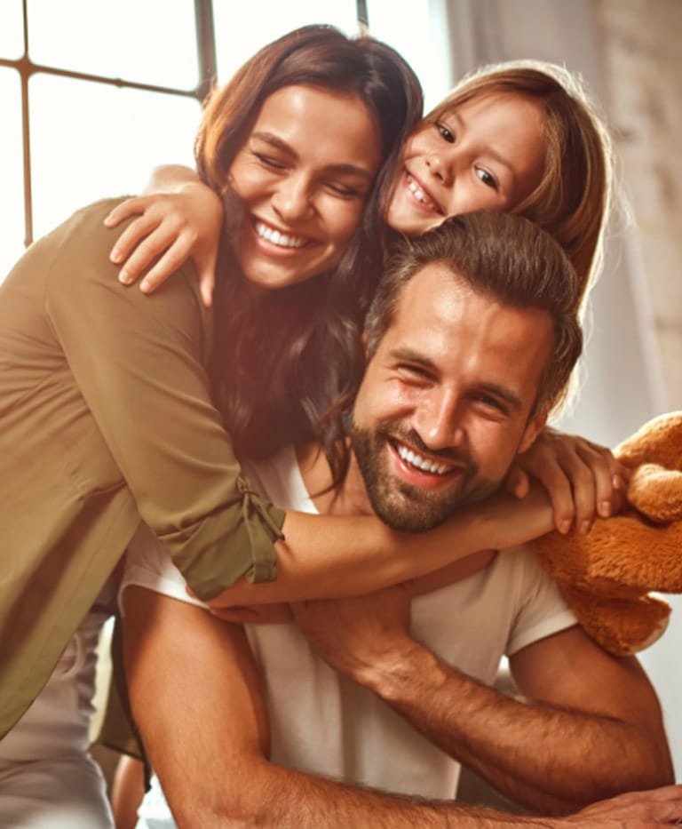 Mother, father, and daughter hugging and smiling