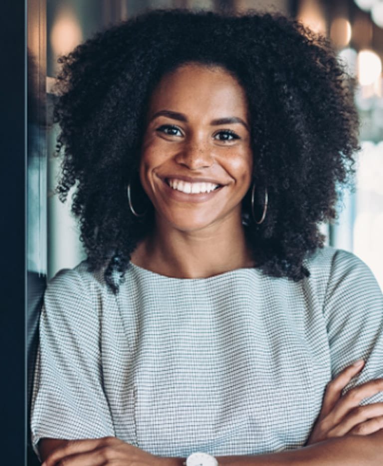 Woman with curly hair smiling wearing a striped shirt