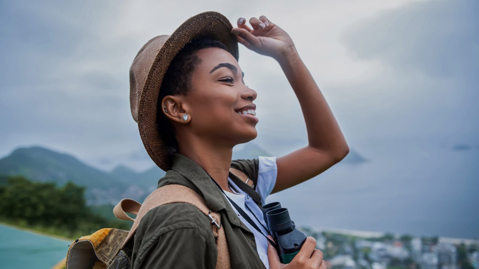 Woman smiling outside, touching her hat